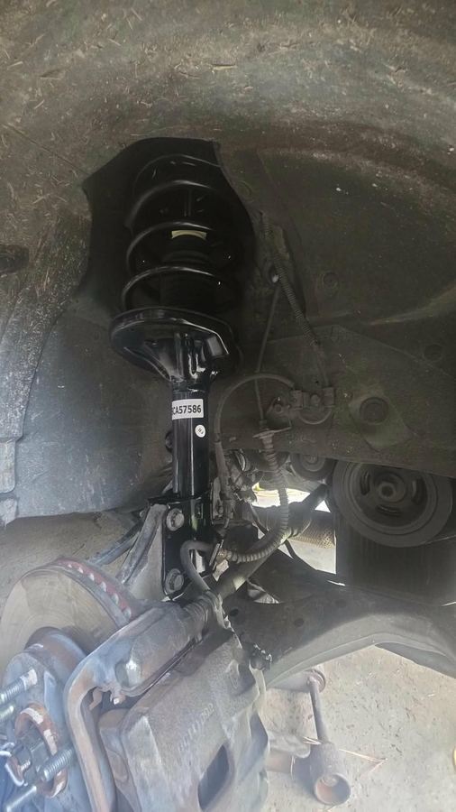 New strut and coil spring assembly installed in a front wheel well