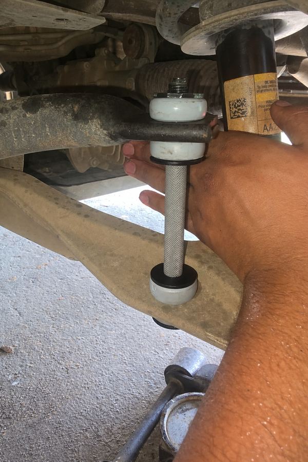 New sway bar end link being fitted to a front control arm